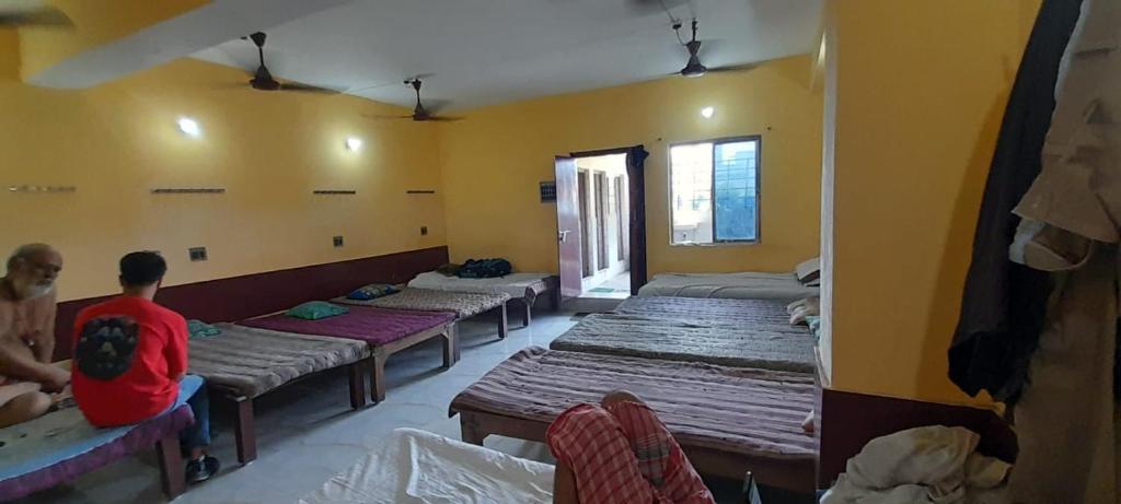 een groep bedden in een kamer waar mensen op zitten bij Narendra niketan in Calcutta