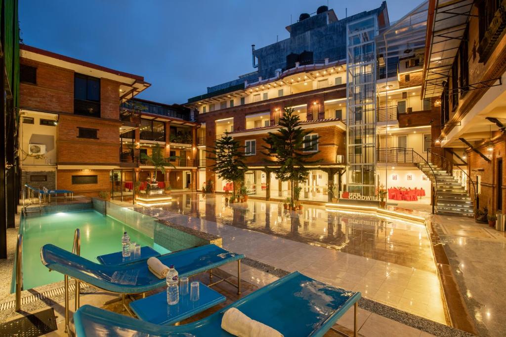 a swimming pool with blue chairs and a building at Hotel Goodwill Pvt Ltd in Kathmandu