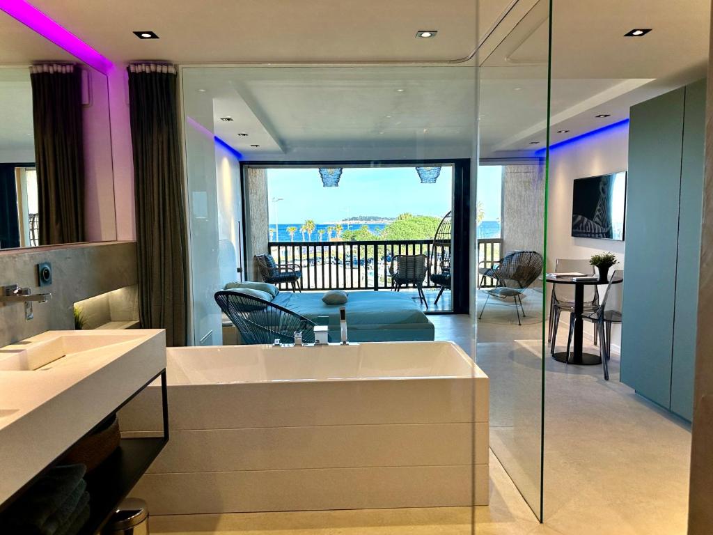 a bathroom with a sink and a living room at Appartement neuf climatisé - vue mer Saint-Tropez - 50m plage et port - piscine in Gassin
