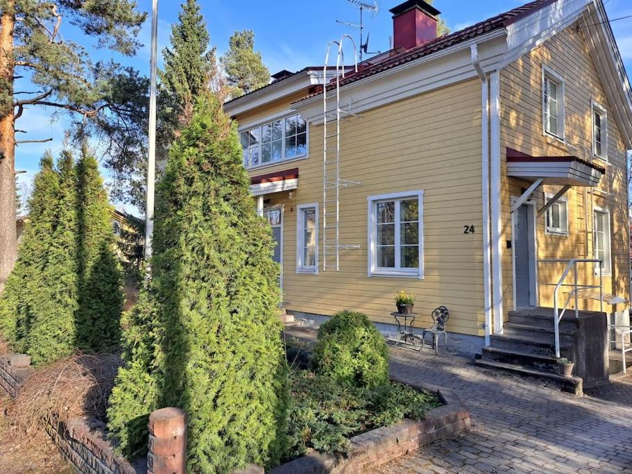 una casa amarilla con árboles delante de ella en Paritalohuoneisto keskustassa, en Valkeakoski