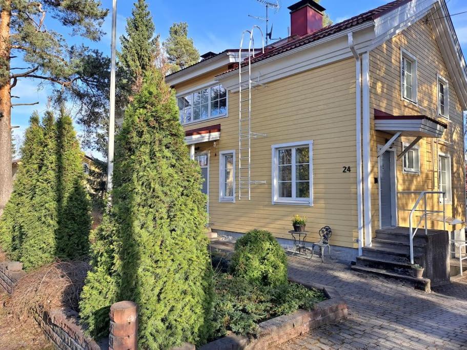 a yellow house with trees in front of it at Paritalohuoneisto keskustassa in Valkeakoski