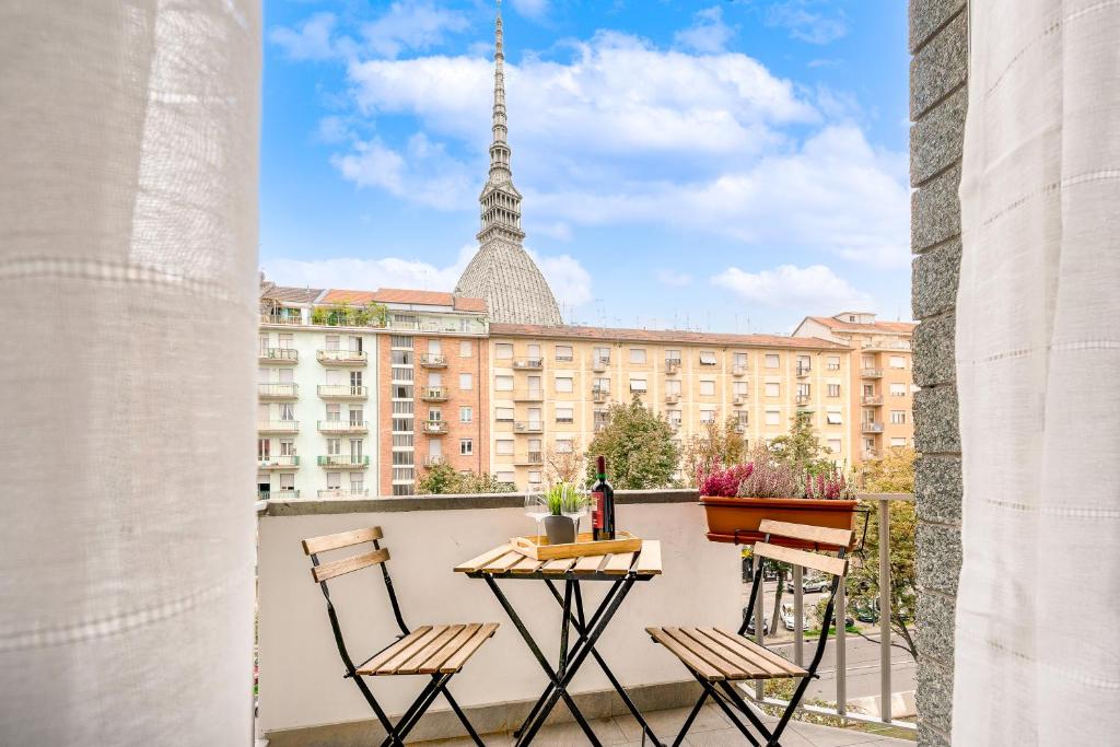 un balcone con tavolo e sedie e un edificio di Vista Mole, Centro a 15 min - Luxury Suites & fast WiFi a Torino