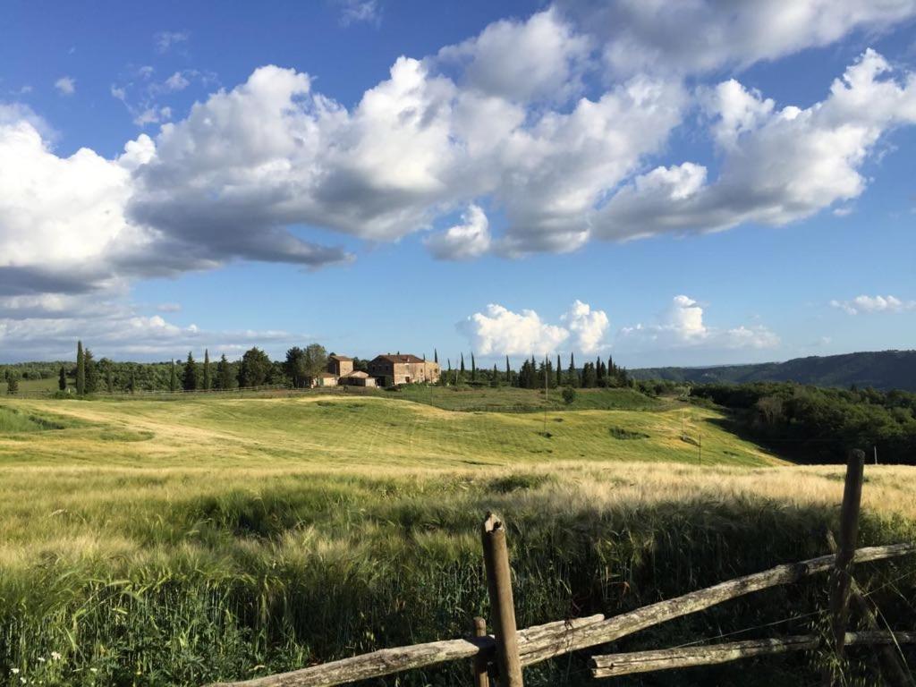 una cerca en un campo con una casa en una colina en La Capretta Country House, en Parrano