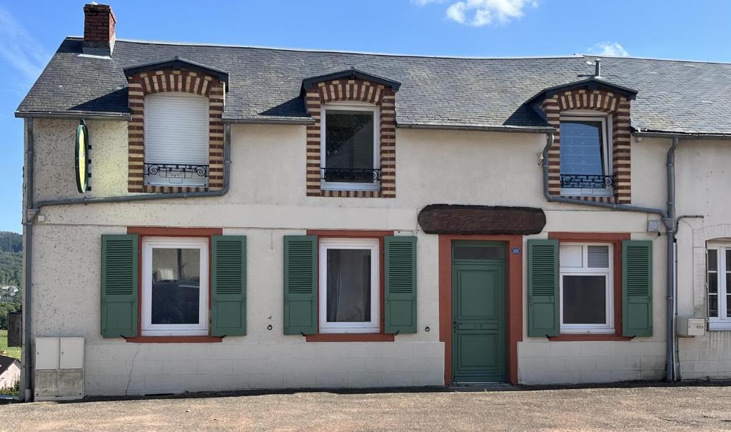 een wit huis met groene deuren en ramen bij Les Logis du Haut-Folin in Arleuf