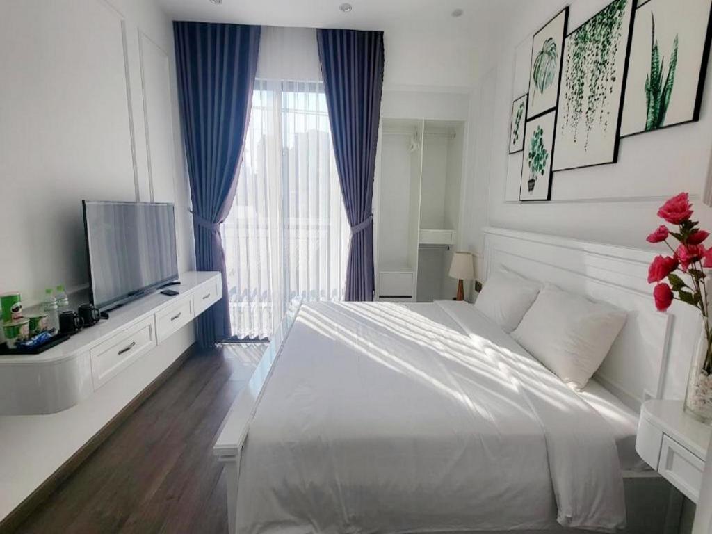 a white bedroom with a large bed and a window at Amy Hotel Hue in Hue
