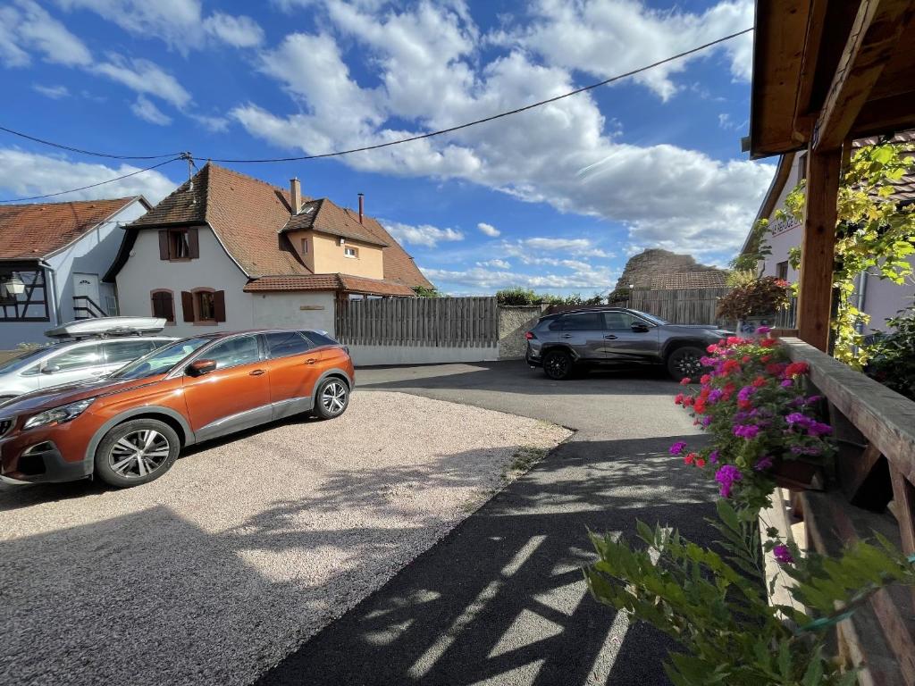 two cars parked in a driveway next to a house at Le Refuge du Rempart in Dambach-la-Ville