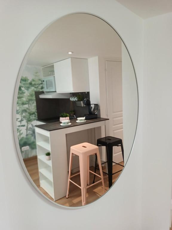 eine kleine Küche mit einem rosa Stuhl und einem Spiegel in der Unterkunft Charmant studio sur Orsay in Orsay
