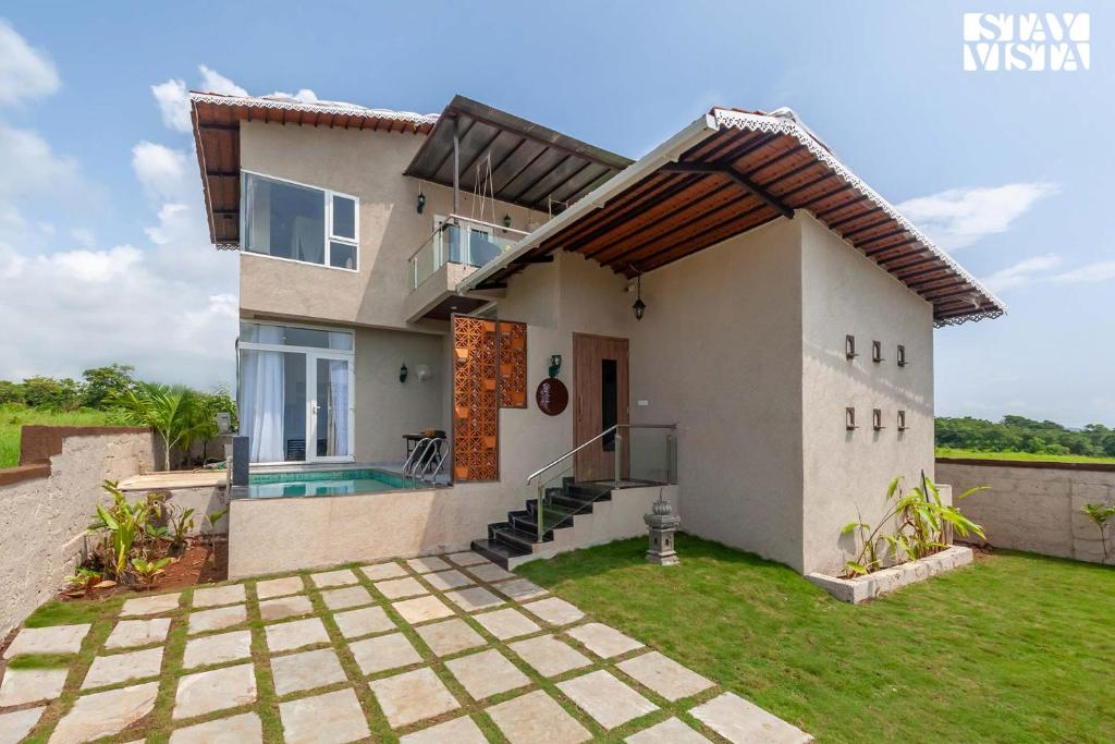 una villa con piscina y una casa en StayVista's Coral Breeze with Plunge Pool, Games Room, Projector Setup, Proximity to Secluded Beach, en Dapoli
