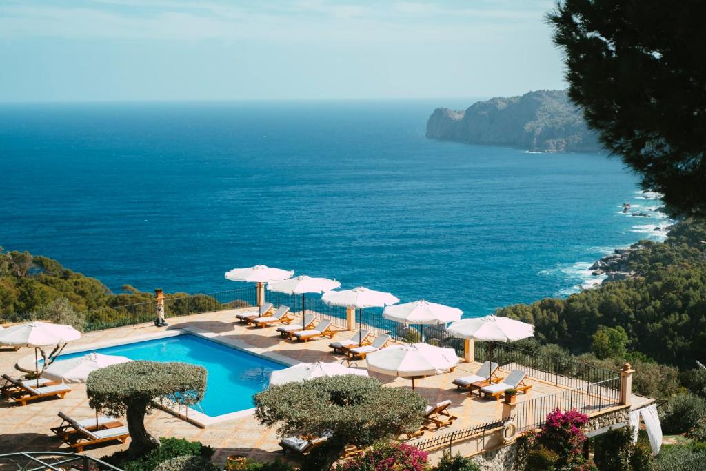 - une piscine avec parasols et chaises et l'océan dans l'établissement Sa Pedrissa, à Deià