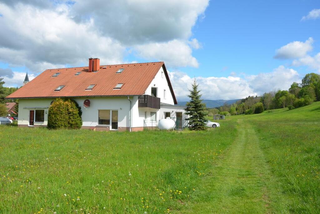 Biały dom z czerwonym dachem na polu w obiekcie Unsere Ferienwohnung Stefan im Riesengebirge! w mieście Dolní Lánov
