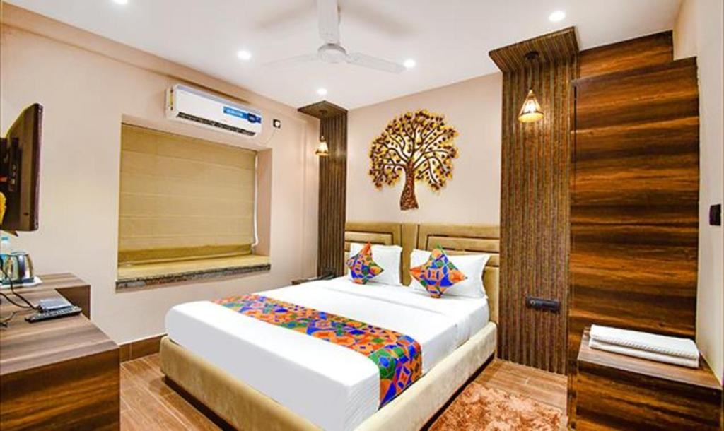 a bedroom with a bed with a tree on the wall at FabHotel Jalsa Residency New Town in Kolkata
