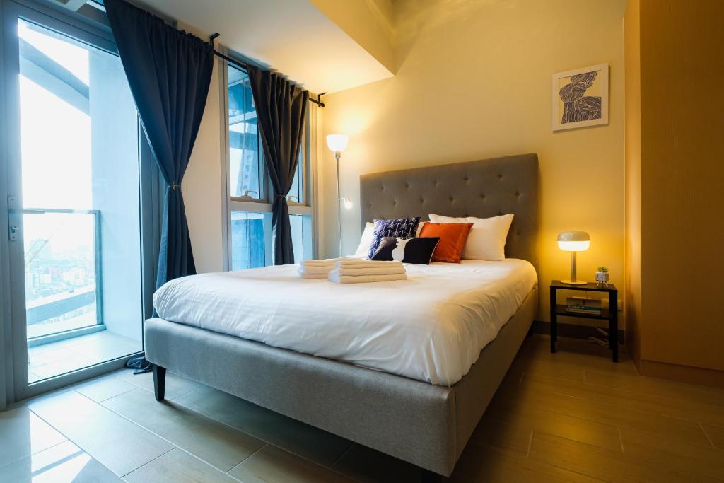 um quarto com uma cama e uma grande janela em Cozy 1BR Apartment in Manila, BGC, with Balcony & Pool em Manila