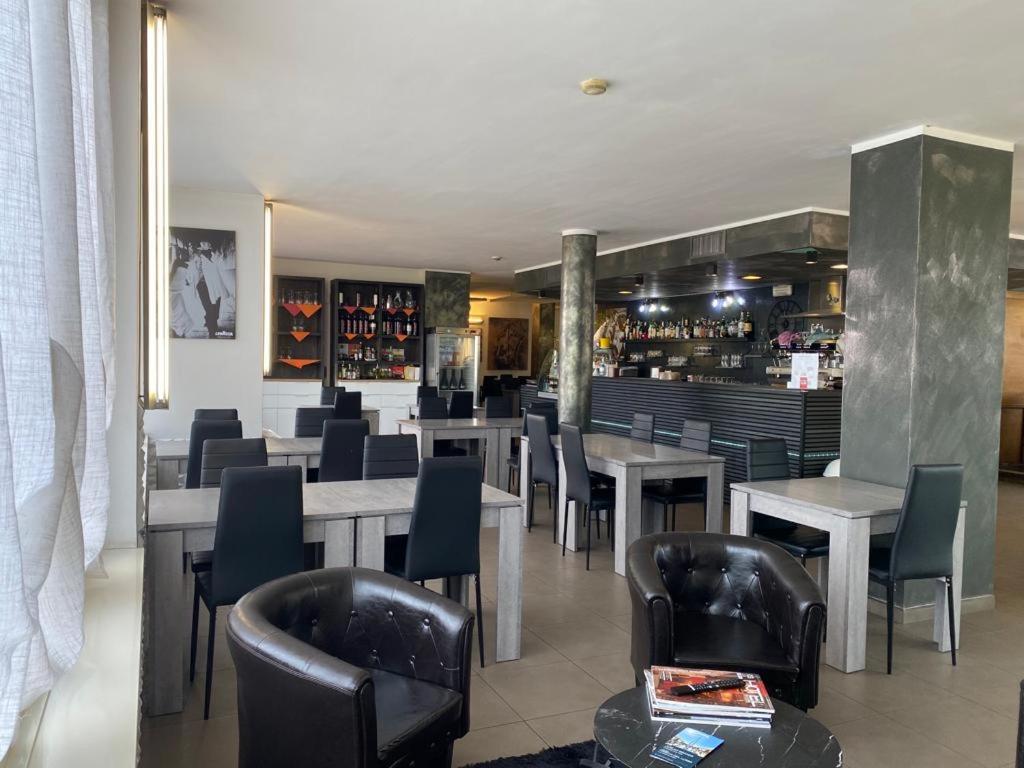 un restaurante con mesas y sillas y un bar en Hotel Verdina, en Volpiano