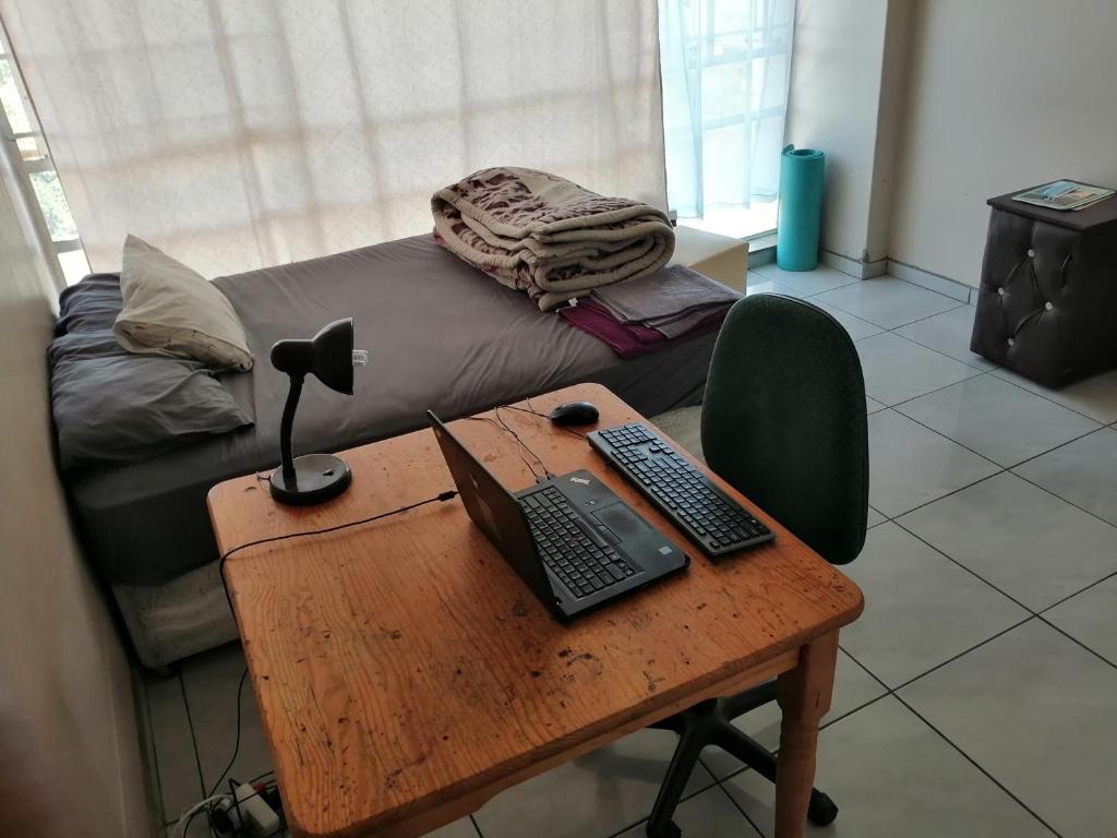 a desk with a laptop and a keyboard and mouse at Kingswood Flats in Pretoria