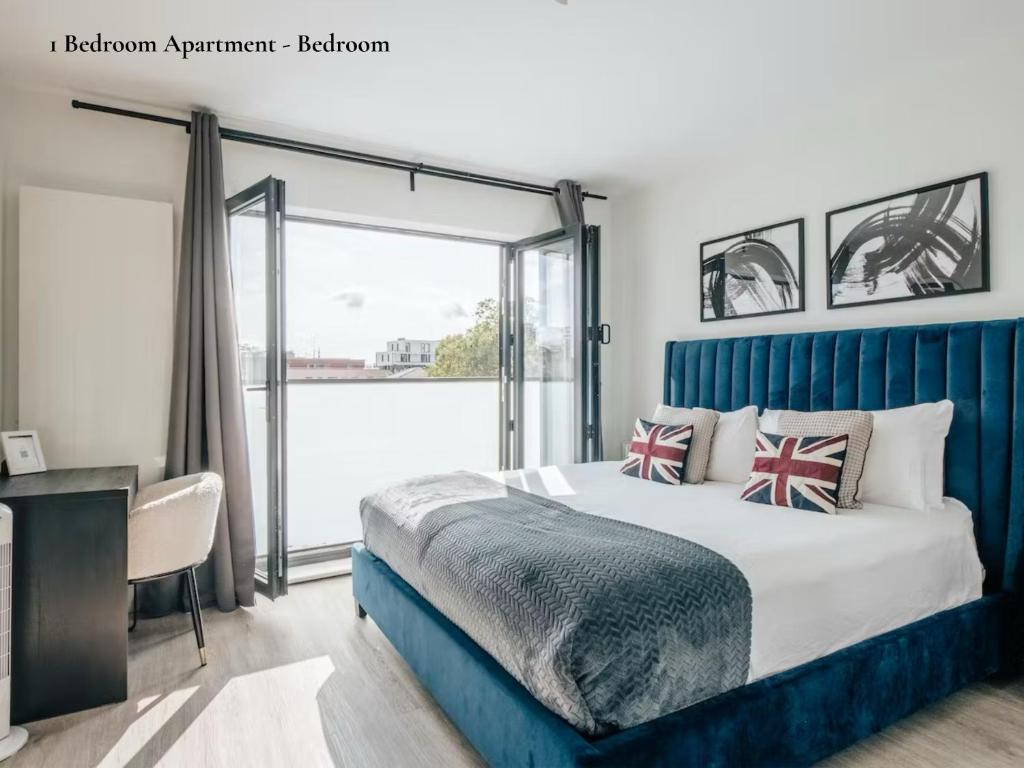 um quarto com uma cama com uma cabeceira azul e uma janela em Lux Bermondsey Apartments Near Tower Bridge em Londres