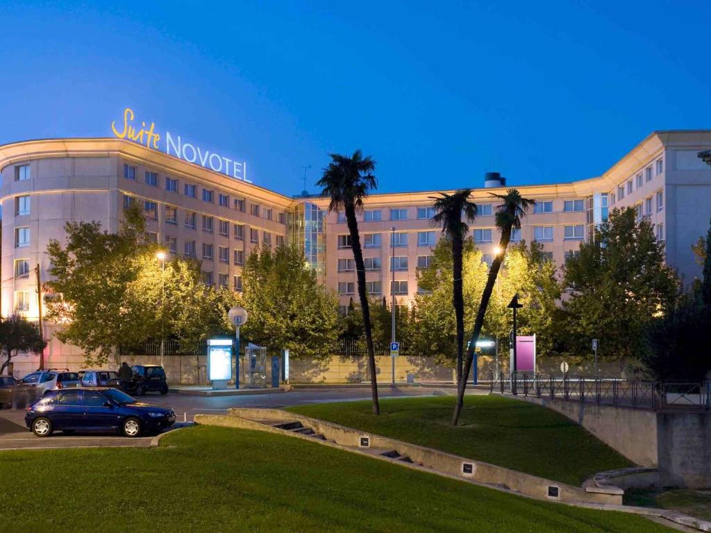 une voiture garée devant un grand bâtiment dans l'établissement Novotel Suites Montpellier Antigone, à Montpellier