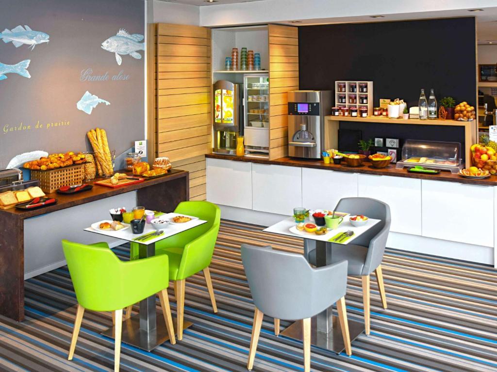 um restaurante com duas mesas e cadeiras verdes em ibis Styles Strasbourg Avenue du Rhin em Estrasburgo