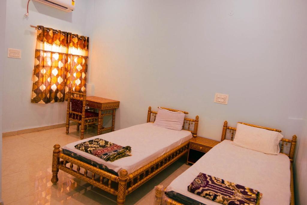 - une chambre avec 2 lits, un bureau et une fenêtre dans l'établissement ISKCON Pandharpur's Chandrabhaga Guest House, à Pandharpur