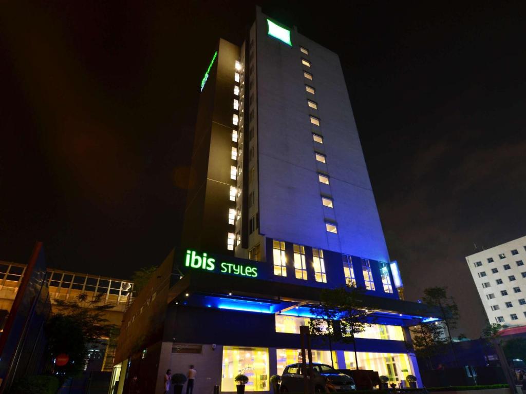 un edificio iluminado con un cartel de servicios de autobús por la noche en ibis Styles Kuala Lumpur Sri Damansara en Petaling Jaya