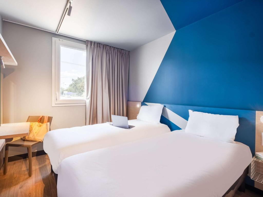 two beds in a room with a blue wall at ibis budget Nantes Nord Treillières in Treillières