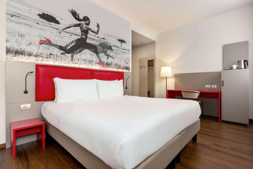 a hotel room with a large bed with a red headboard at Amedia Milano, Trademark Collection by Wyndham in Milan