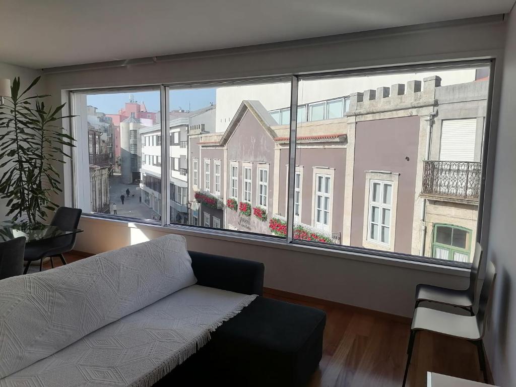 uma sala de estar com um sofá e uma grande janela em Garrett Houses em Póvoa de Varzim
