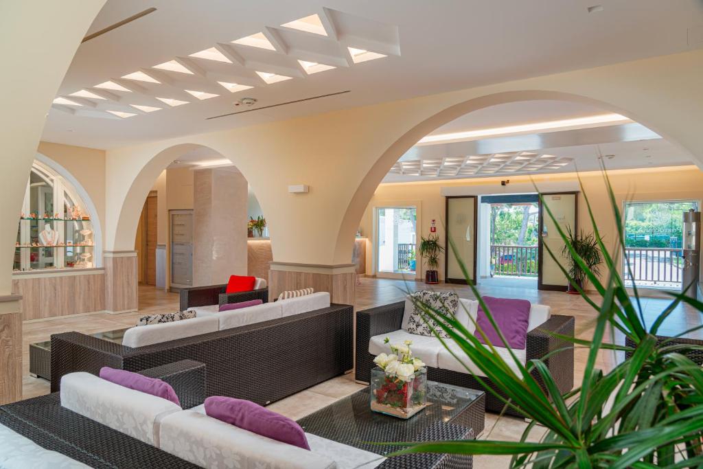 een woonkamer met 2 banken en paarse kussens bij Hotel Portoconte in Porto Conte