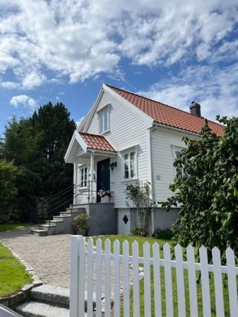 a white house with a white fence in front of it at Hybel med bad in Egersund