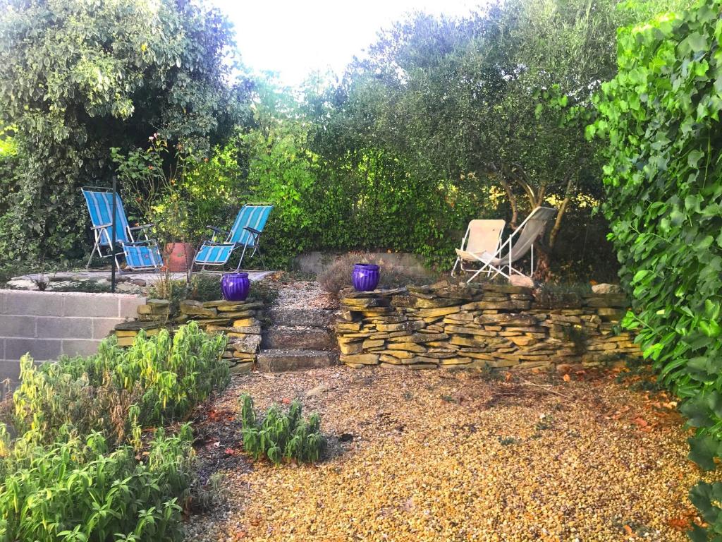 a yard with two chairs and a stone wall at Les Lauriers in Limoux