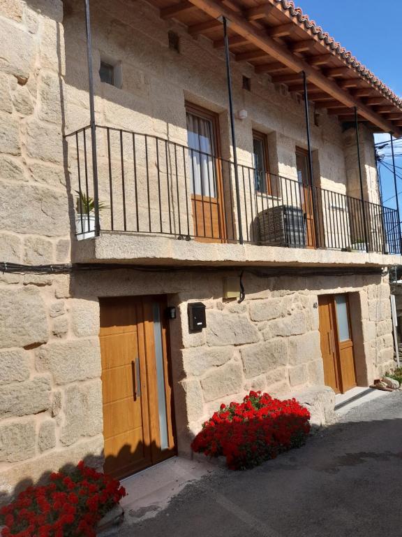 a stone building with a balcony and red flowers at Casa MENDEZ - ALLARIZ in Ourense