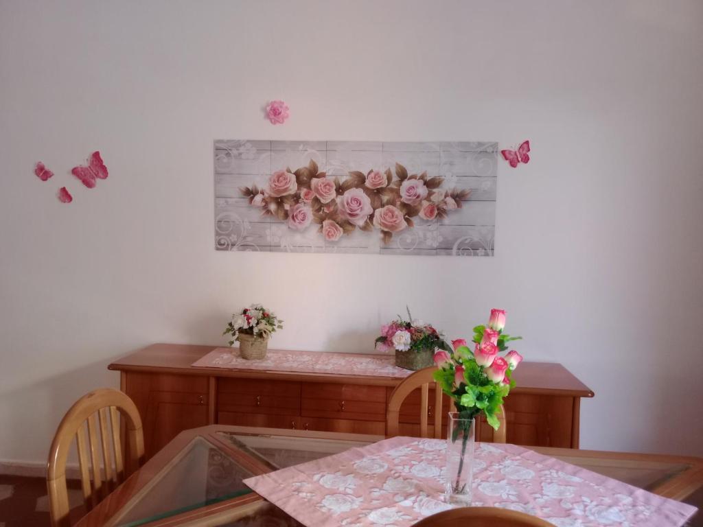 einen Tisch mit einer Blumenvase an der Wand in der Unterkunft Appartamento vacanze Le rose in Bosa