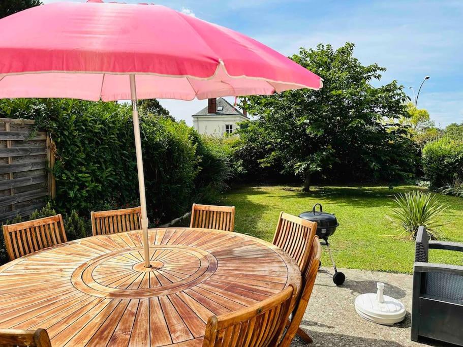 een houten tafel met een rode paraplu in een tuin bij Superbe maison spacieuse avec jardin in Angers