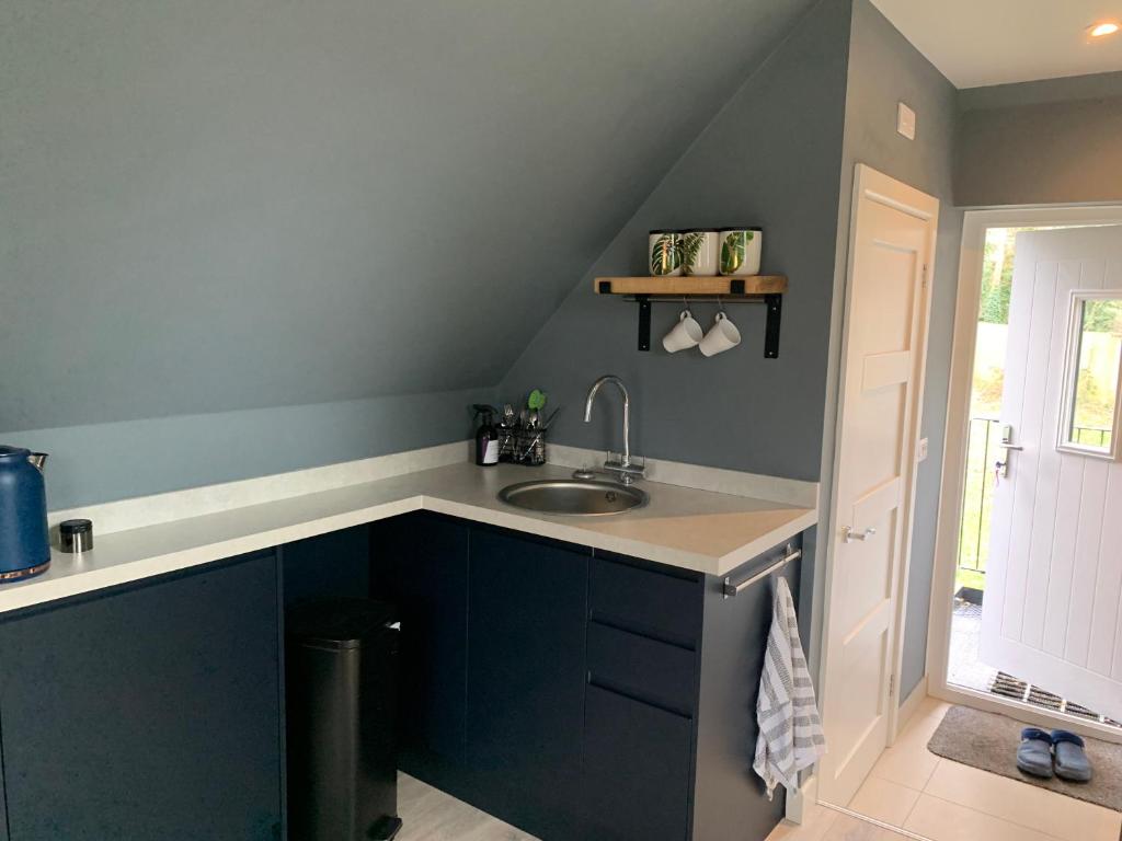 a kitchen with a sink and a blue wall at The Hay Loft in Warnham