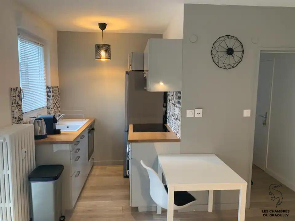 a small kitchen with a white table and a table and a counter at Les chambres du Graoully - Le 136 - Metz Queuleu - Place de parking intérieur in Metz
