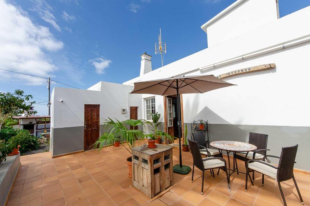 a patio with a table and chairs and an umbrella at Pino Redondo in Puntagorda