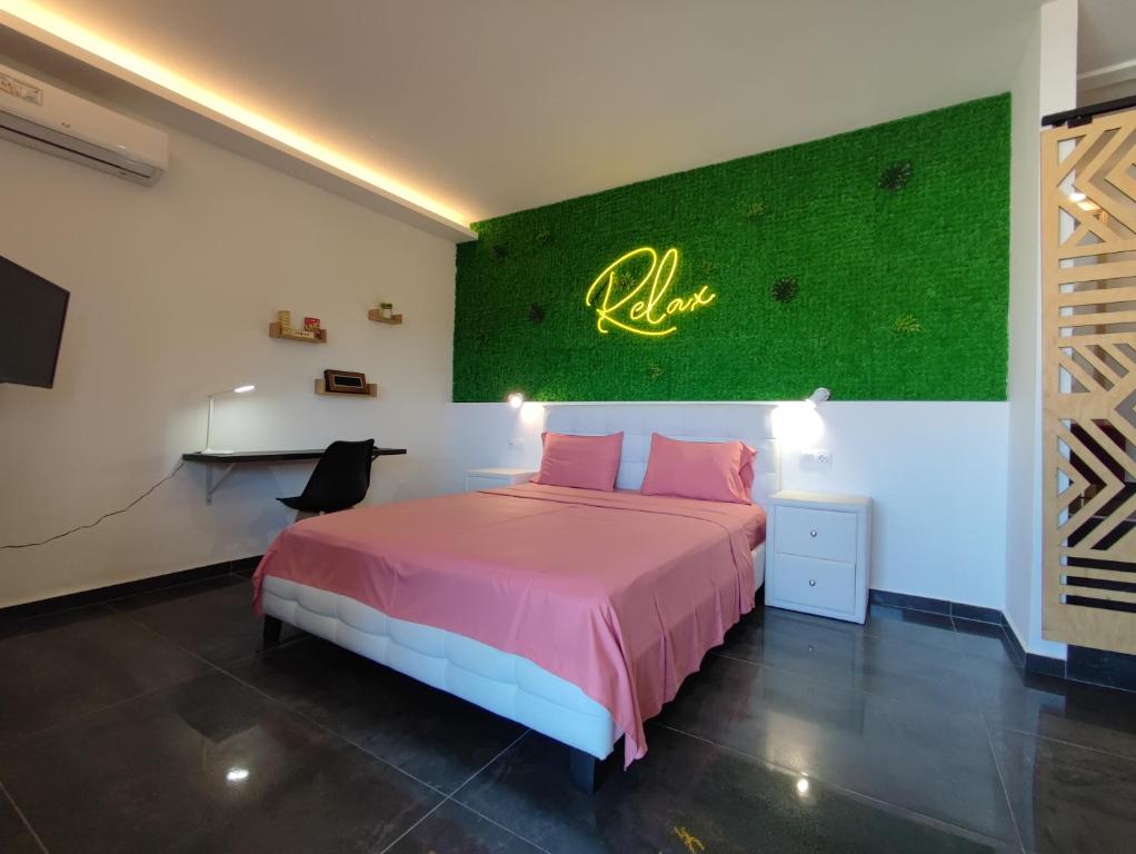 a bedroom with a pink bed and a green wall at THEASIS 4 luxury studio with sea view in Neos Marmaras
