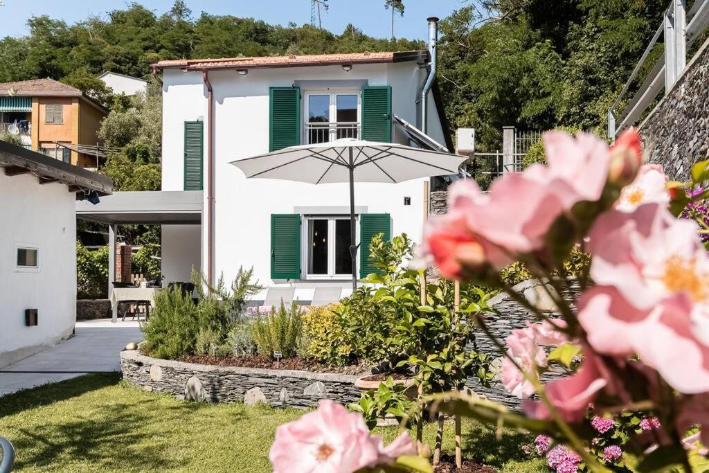 een wit huis met groene luiken en een paraplu bij Das Casa Liguria - Luxuriöses Ferienhaus nur 5 Gehminuten vom Strand - Cinque Terre & Sestri Levante in Lavagna