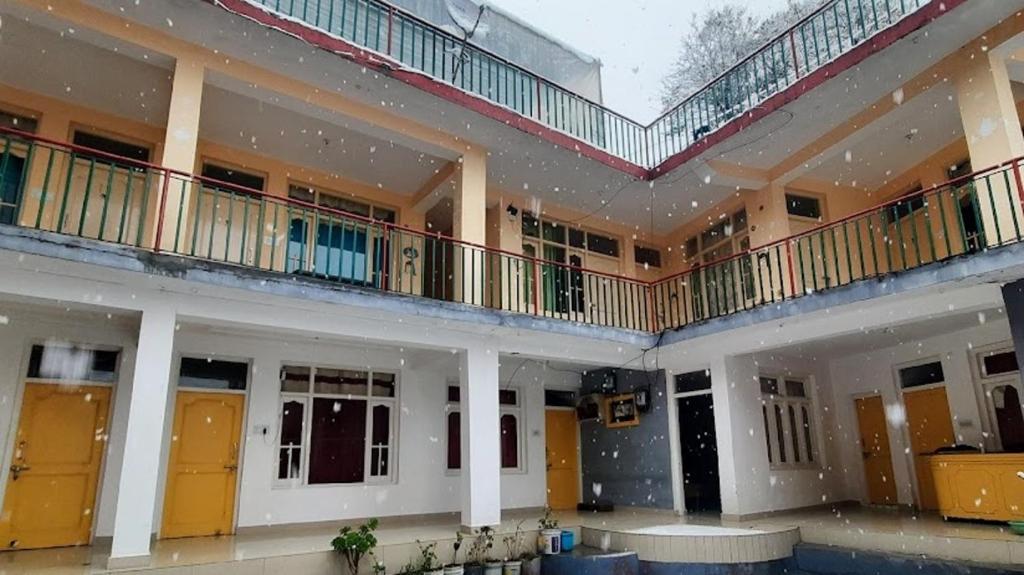 a large building with yellow doors and balconies at Be Happy HomeStay in McLeod Ganj
