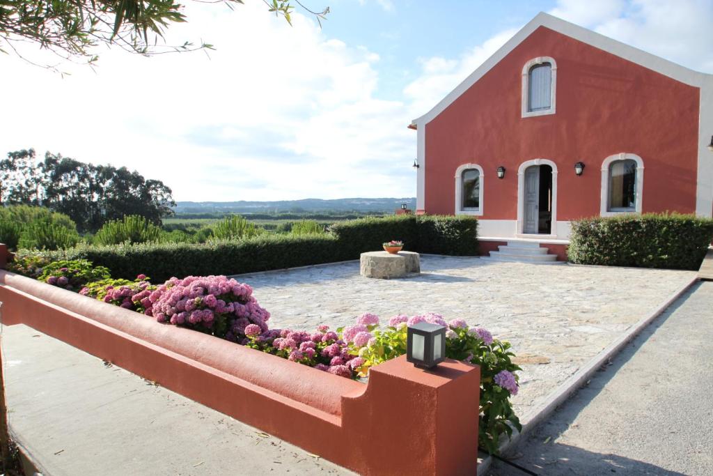 een rode kerk met een bloementuin ervoor bij Quinta das Soizas - São Martinho in Alfeizerão