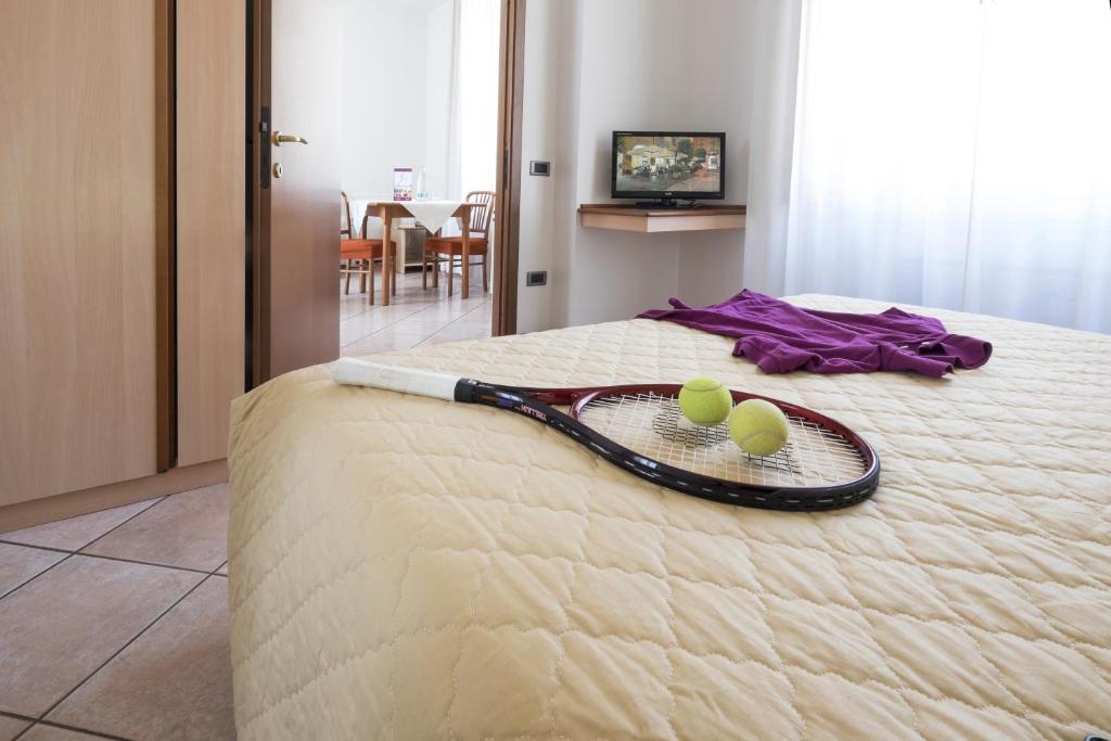 einen Tennisschläger und zwei Tennisbälle auf einem Bett in der Unterkunft Residence XX Settembre in Alba