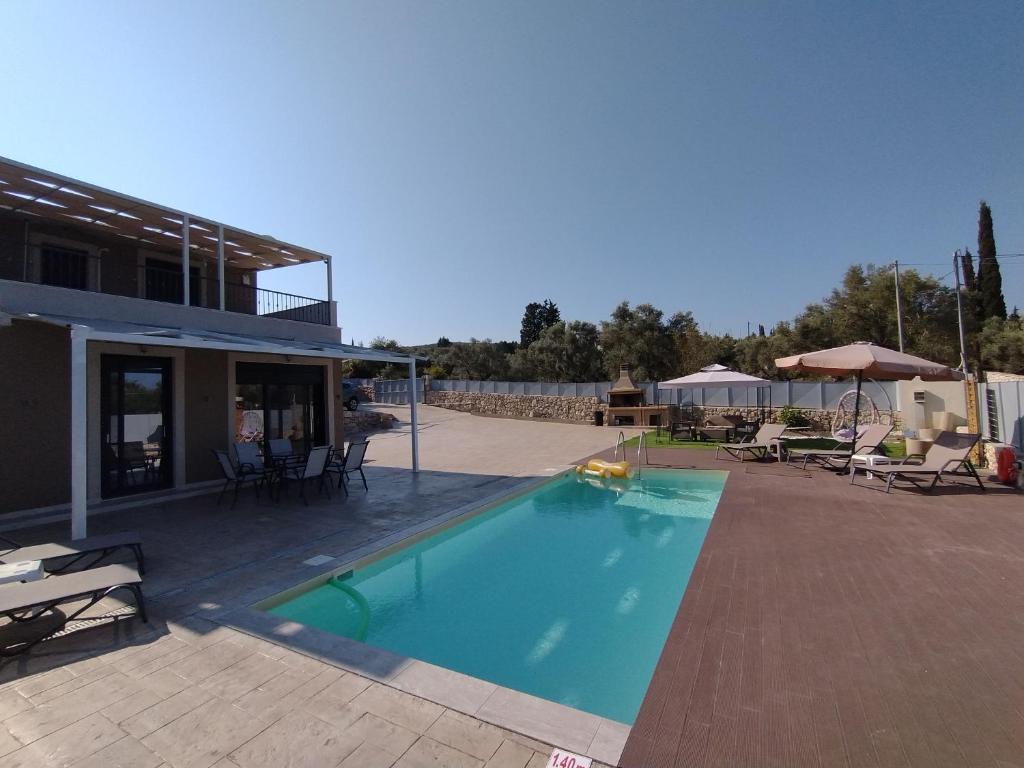 a swimming pool with chairs and umbrellas next to a house at VILLA NDJ RELAX in Tsoukalades