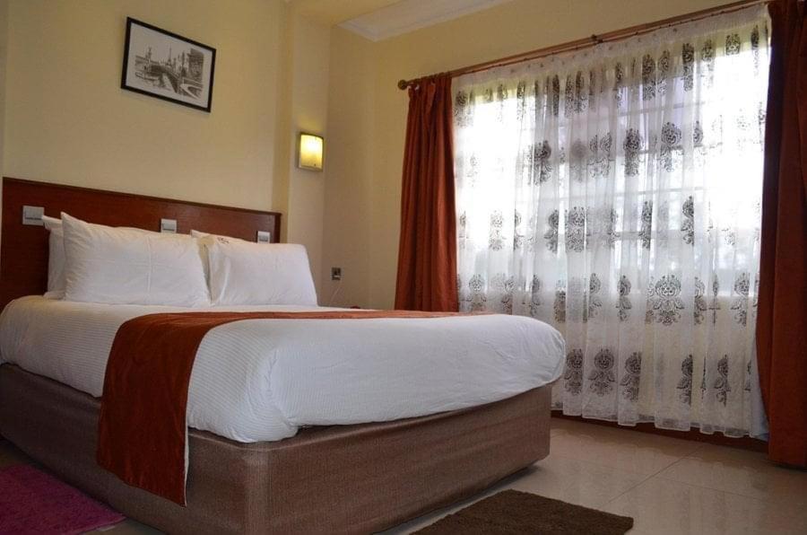 Un dormitorio con una cama grande y una ventana en Brownies Deluxe en Nakuru