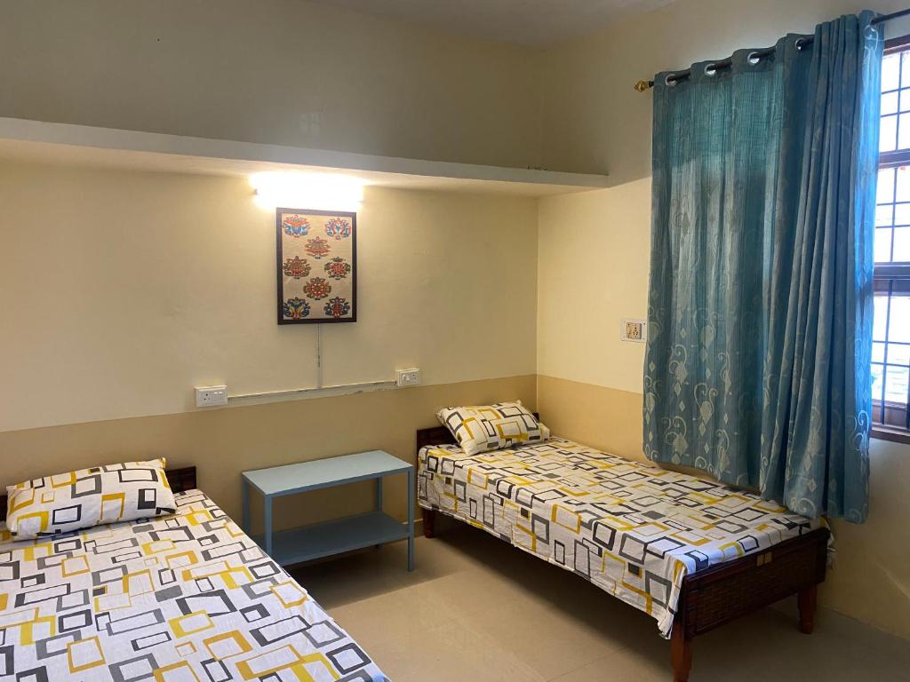 a room with two beds and a table in it at Negi Lodge Chandigarh in Chandīgarh