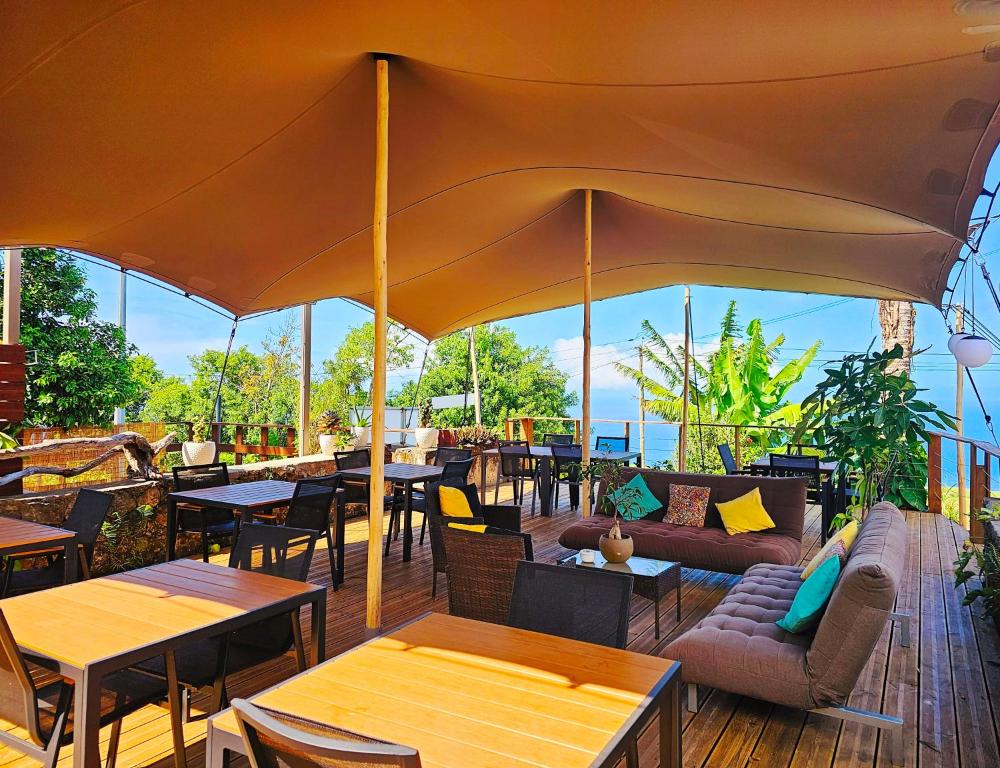 eine Terrasse mit Tischen und Stühlen und einem großen Sonnenschirm in der Unterkunft Domaine de l'Anse in Petite Île