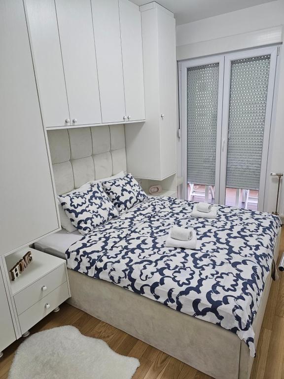 Schlafzimmer mit einem Bett mit einer blauen und weißen Bettdecke in der Unterkunft Apartman Blok 51 in Banja Luka