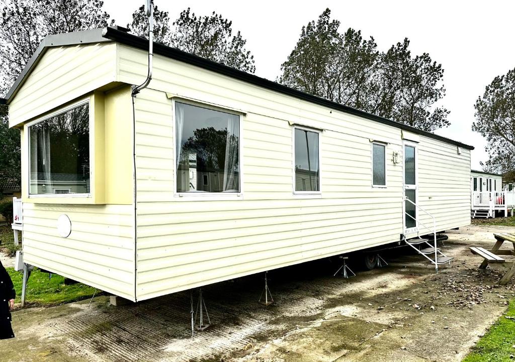 a white tiny house is parked in a yard at Goldflinch - 3 bedroom (8 birth) caravan Sand Le Mere in Waxholme