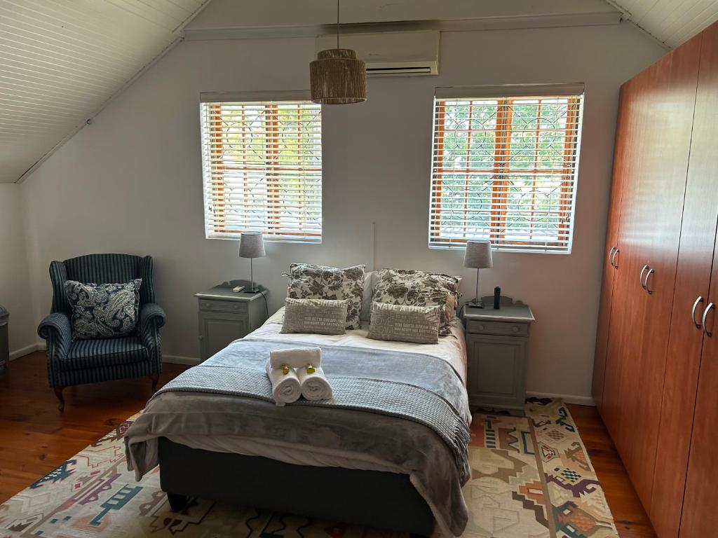 Un dormitorio con una cama y una silla y ventanas. en Paradyskloof Suite, en Stellenbosch