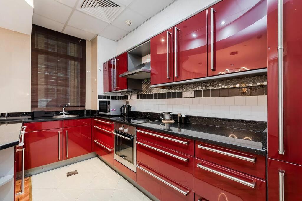 a red kitchen with black counters and red cabinets at Spacious 2BR apartment in Marina Crown in Dubai