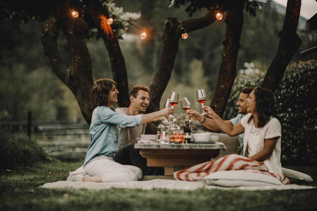 um grupo de pessoas sentadas em torno de uma mesa bebendo vinho em Apfelhotel Torgglerhof em Saltusio
