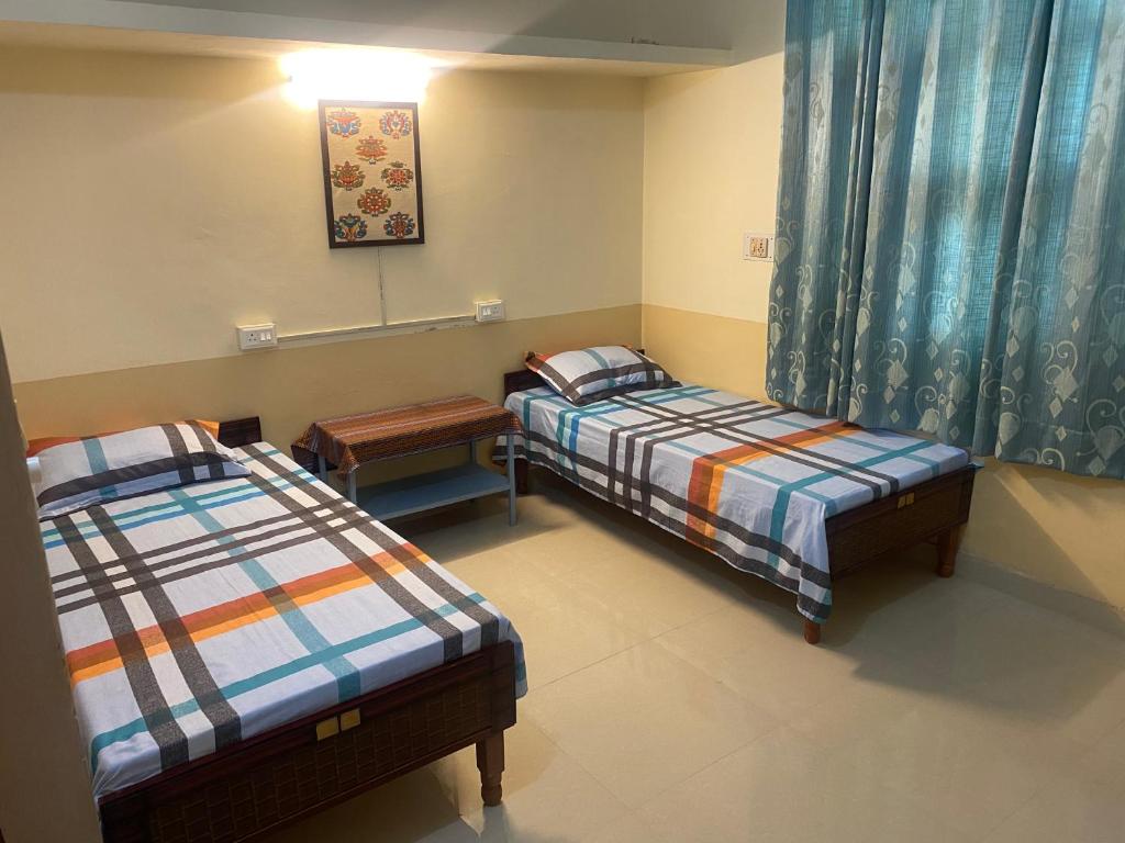 a room with two beds and a table in it at Negi Lodge Chandigarh in Chandīgarh